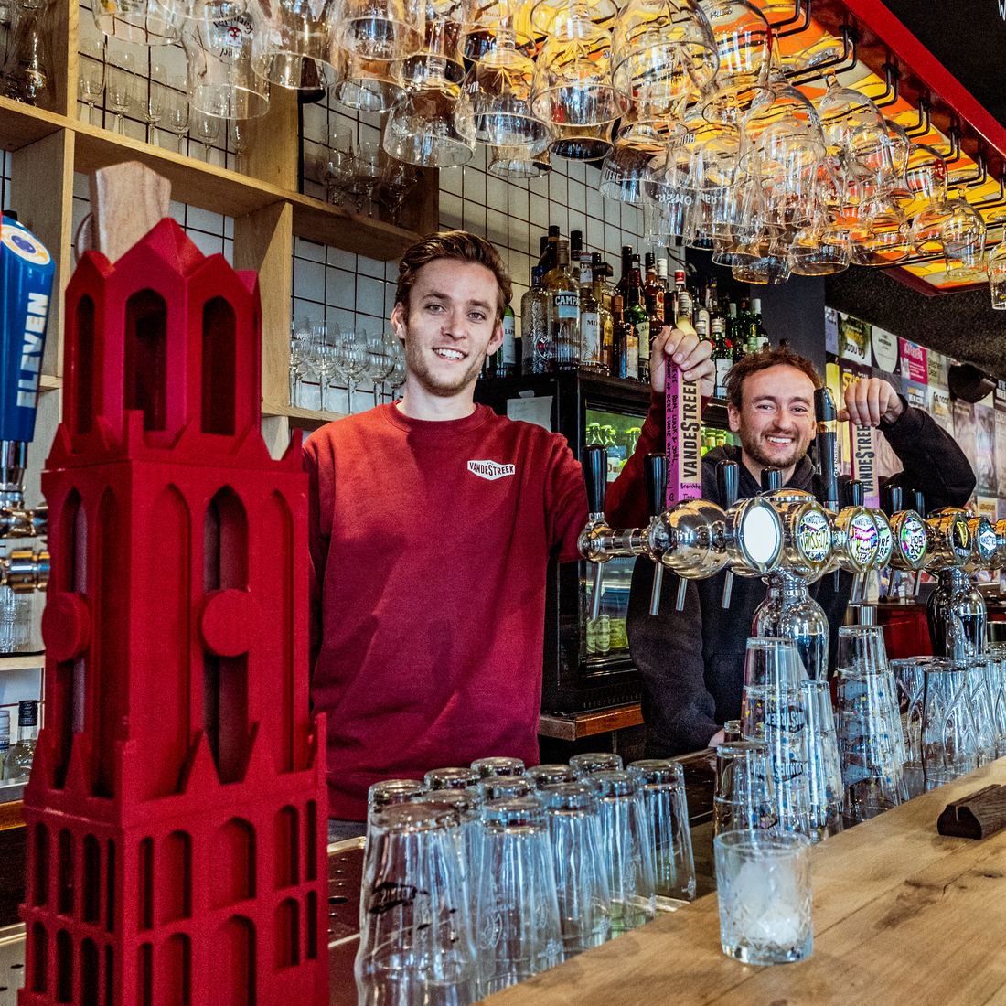Lukas Ausems en Ronald Lentz achter de tap van Café Lombok, met een rode Domtoren op de bar