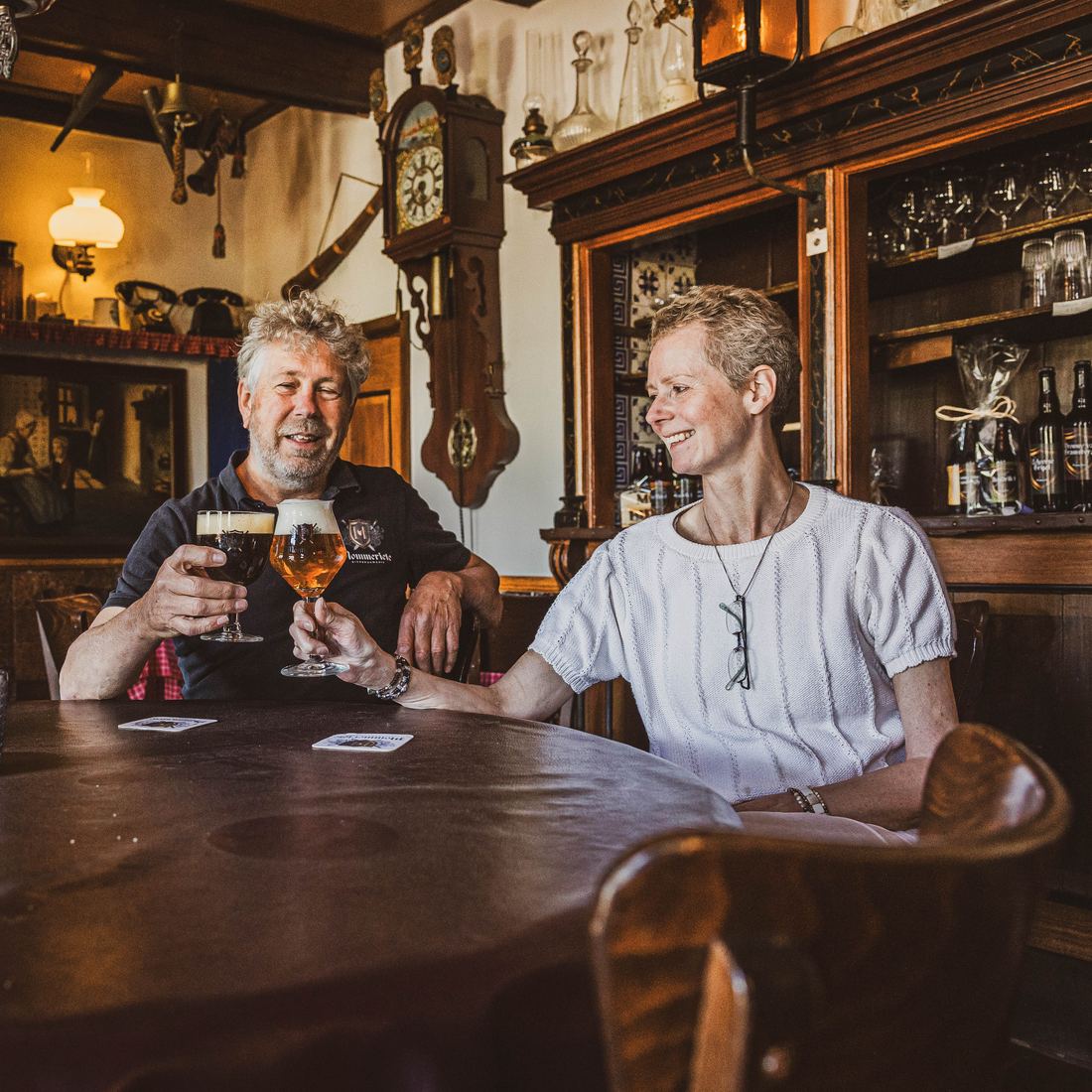 Gert en Carina Kelder proosten met twee glazen Mommeriete-bier aan een houten tafel